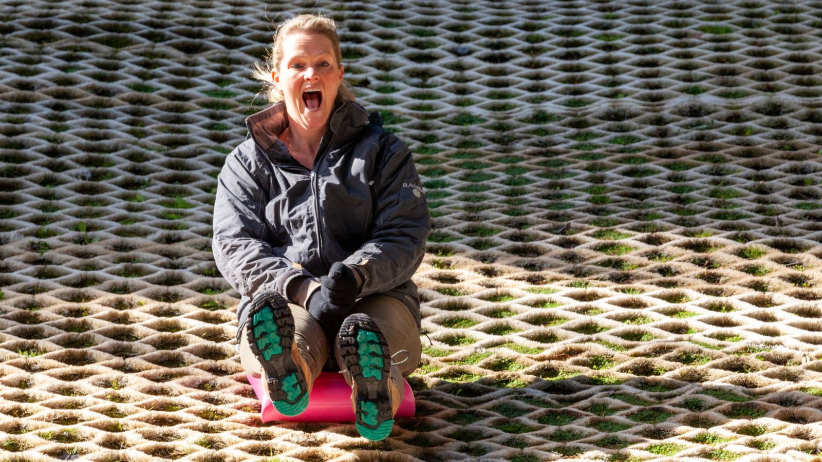 A woman having fun on a sledge at the dry ski slope